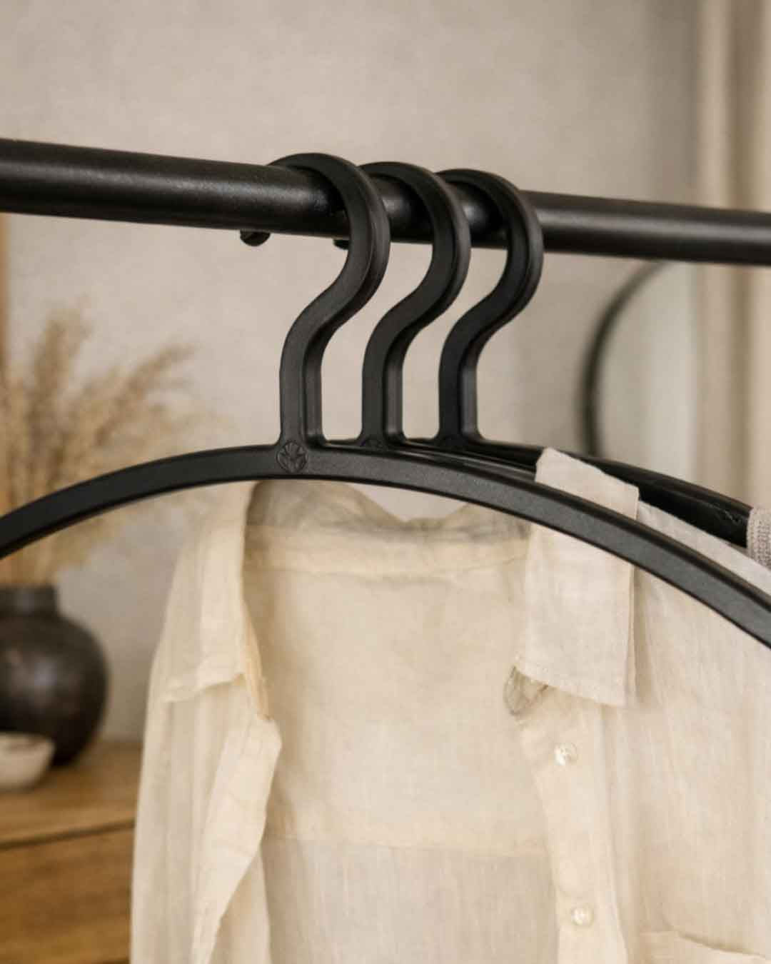 Kleiderbügel FAY in Schwarz an einer Garderobenstange mit heller Bluse im modernen Wohnambiente