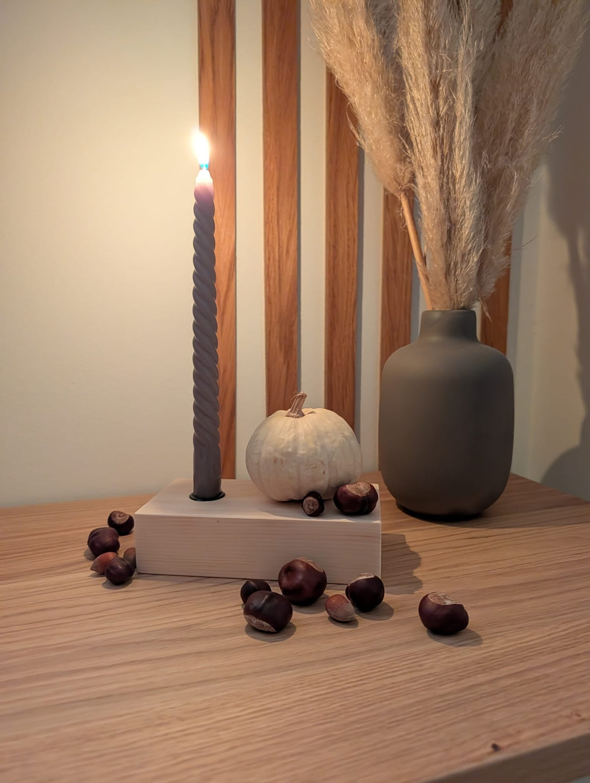 Kerzenständer aus Zirbe mit Deko und brennender Kerze auf Sideboard