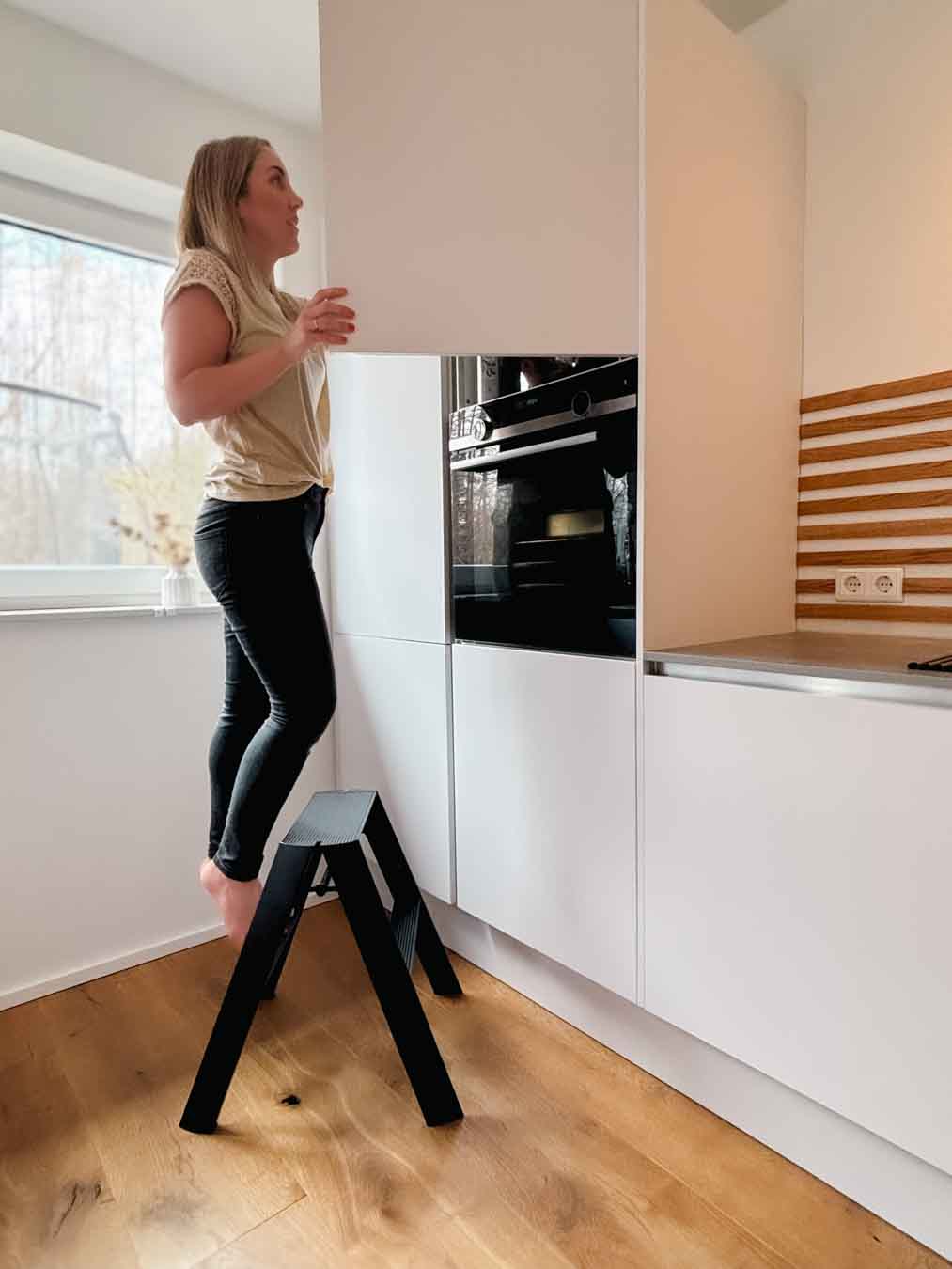 Schwarze Design-Leiter ALVA Duo in einer modernen Küche mit Person in Anwendung