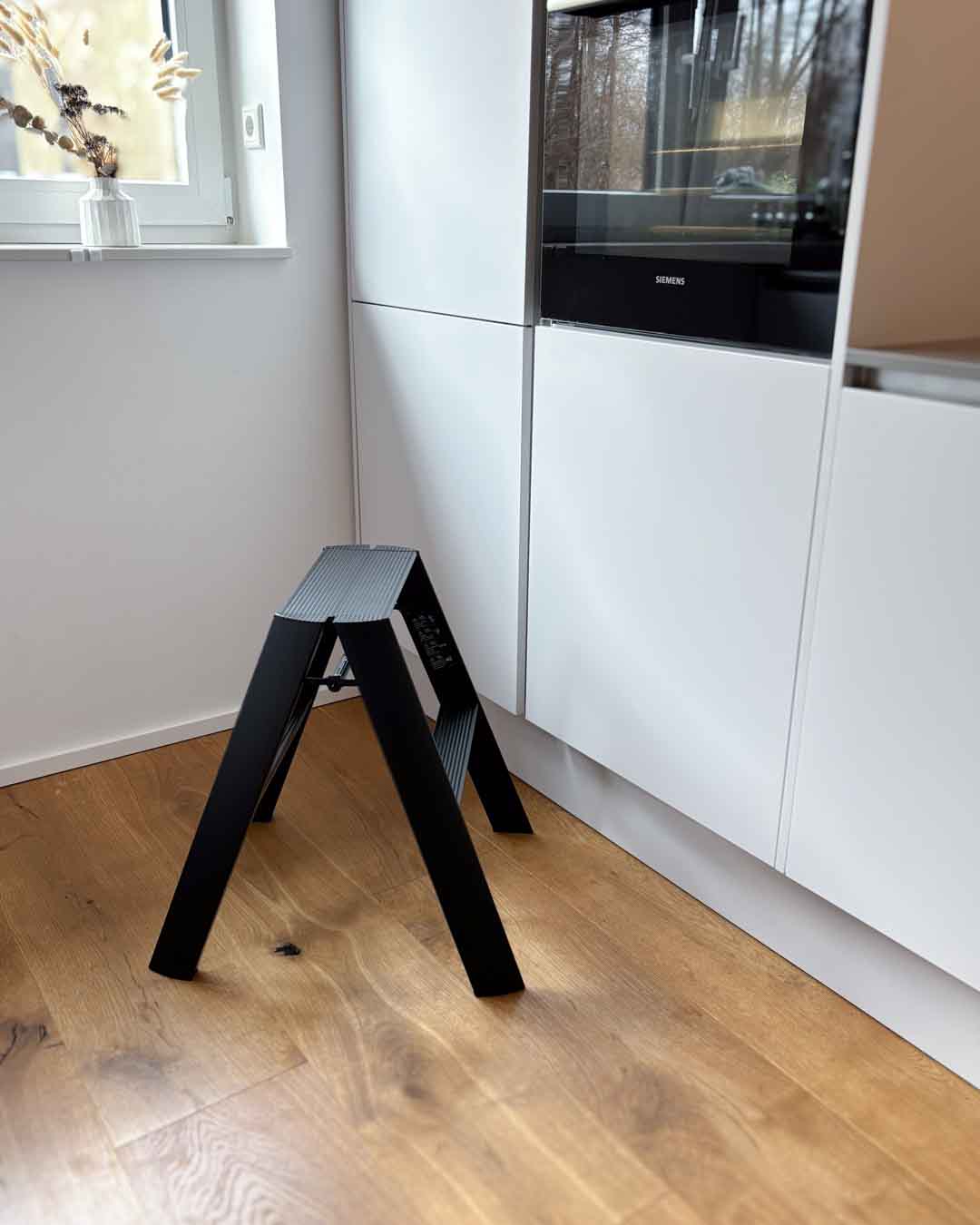 Schwarze Design-Leiter ALVA Duo in einer modernen Küche neben weißen Schränken