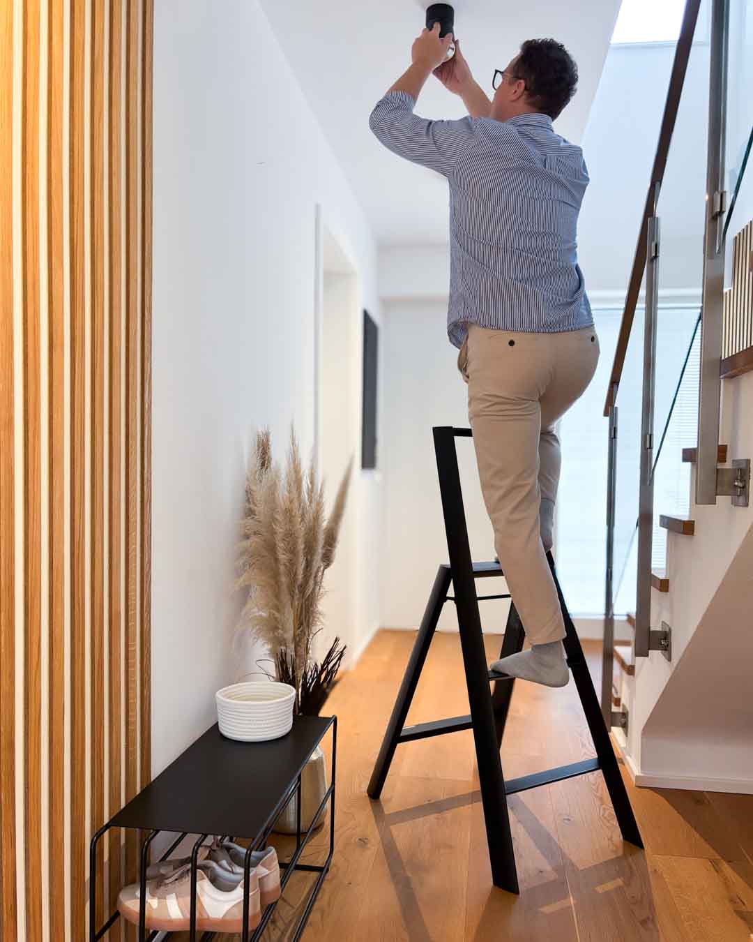 Schwarze Design-Leiter ALVA Trio mit 3 Stufen im Flur mit Person in Anwendung