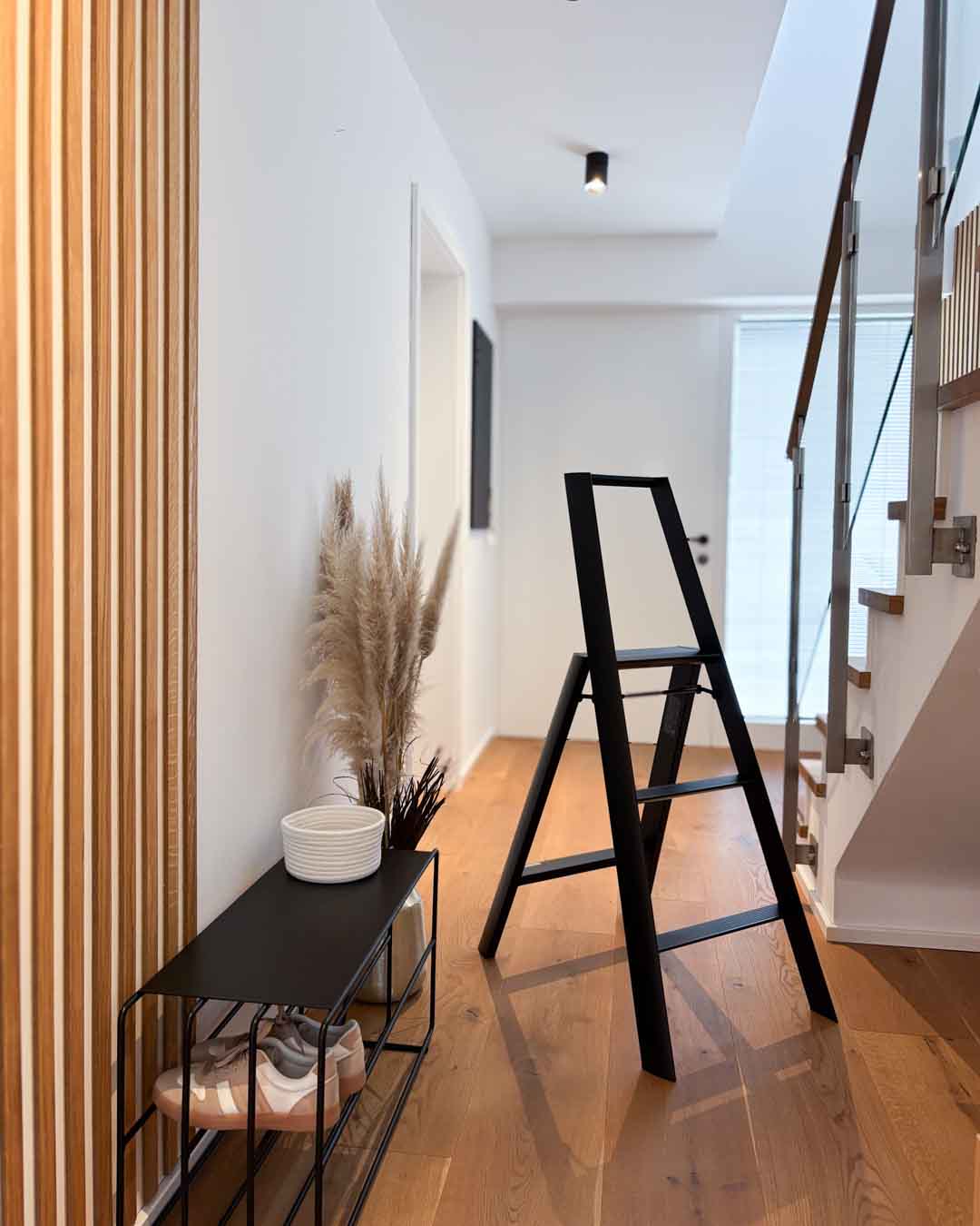 Schwarze Design-Leiter ALVA Trio mit 3 Stufen im Flur neben einer schwarzen Schuhbank