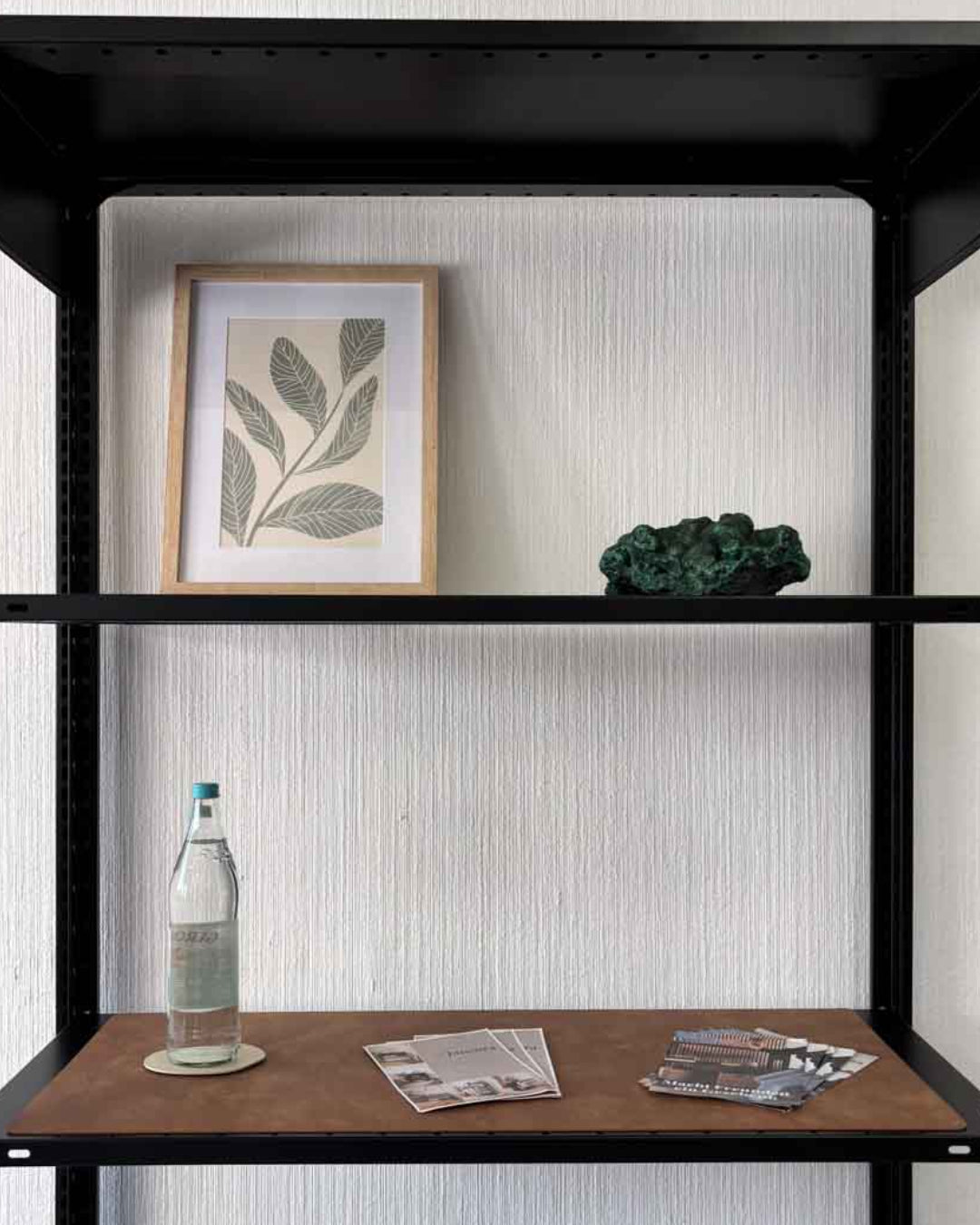 Braune Design-Unterlage 90x38 cm aus recyceltem Leder auf einem schwarzen Design-Regal mit Flasche und Gläsern