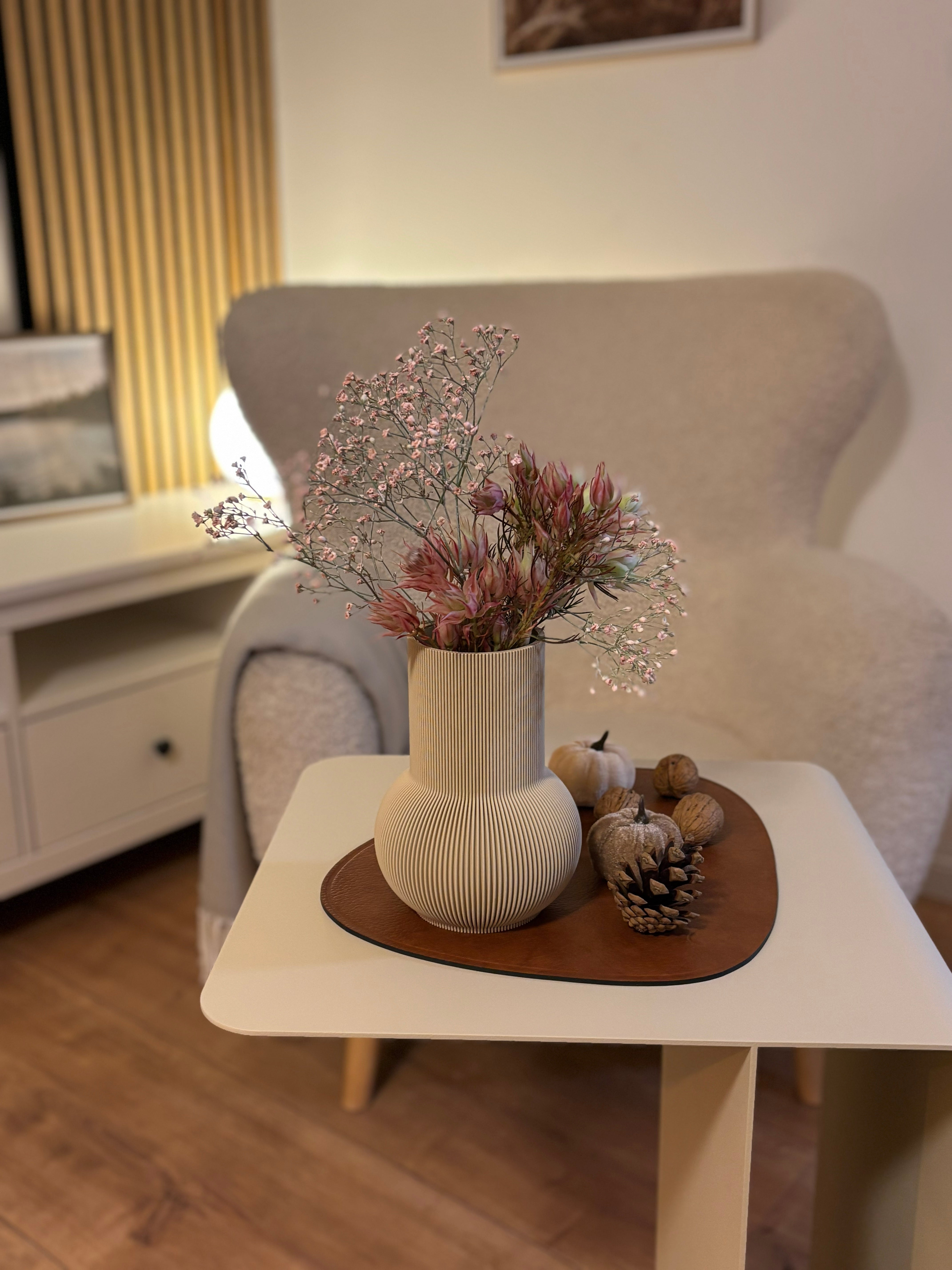 Beige Designvase PURE mit Trockenblumen auf beigem Beistelltisch COSMO mit Sessel im Hintergrund
