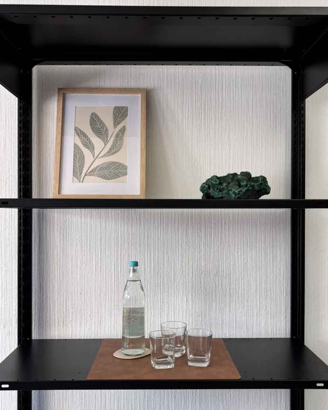 Braune Design-Unterlage 43x38,5 cm aus recyceltem Leder auf einem Design-Regal mit Flasche und Gläsern