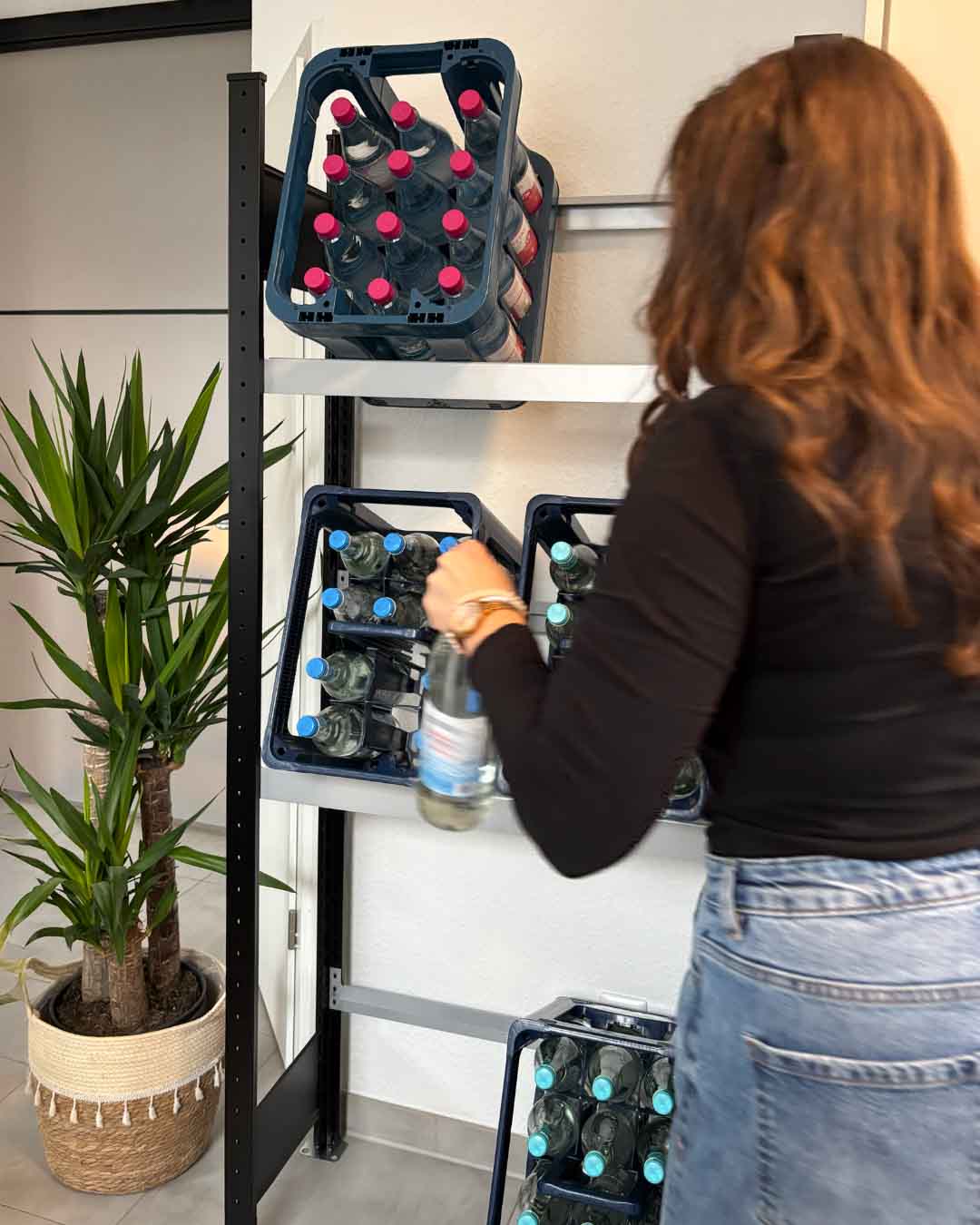 Schwarzes Getränkekistenregal PALO für 6 Kästen mit Person beim Entnehmen einer Flasche