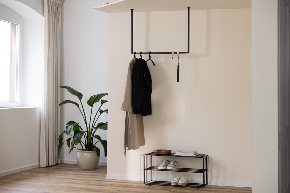 Schwarze RUBI Garderobenstange im Eingangsbereich mit Kleidung und Schuhregal