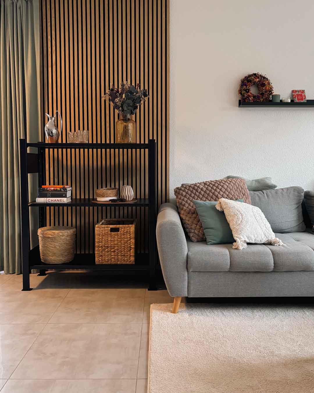 TILO Design Standregal aus Stahl mit Büchern und Deko im modernen Wohnzimmer neben einer Couch mit Kissen