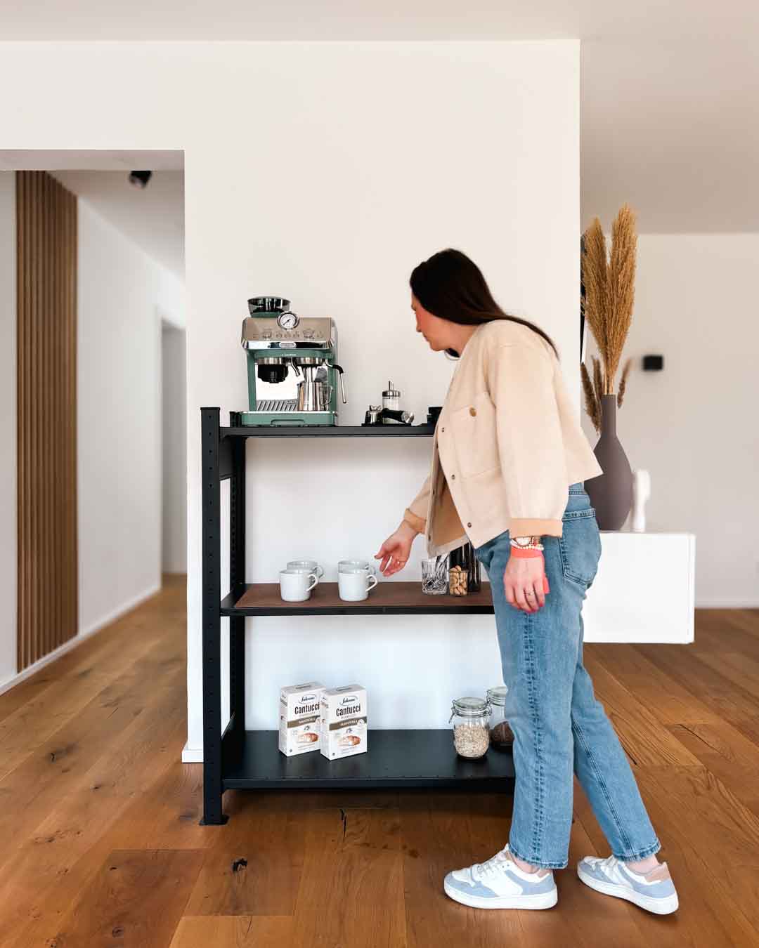 Schwarzes TILO Design Standregal aus Stahl mit 120 cm Höhe im Wohnraum mit Person in Anwendung