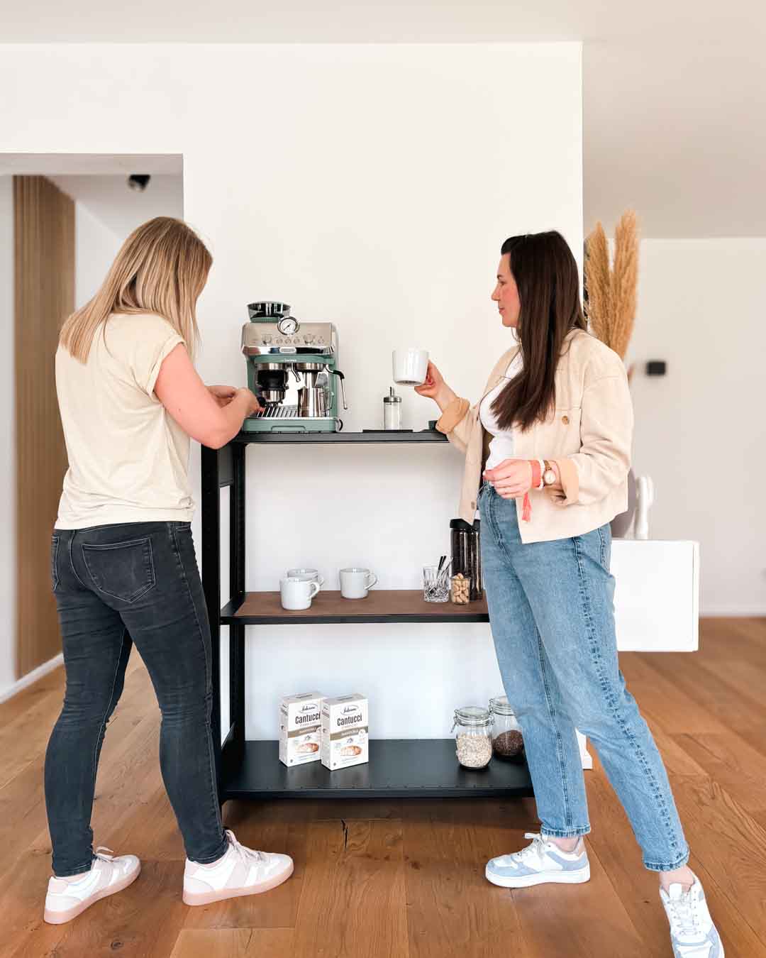 Schwarzes TILO Design Standregal aus Stahl mit 120 cm Höhe im Wohnraum mit zwei Personen in Anwendung