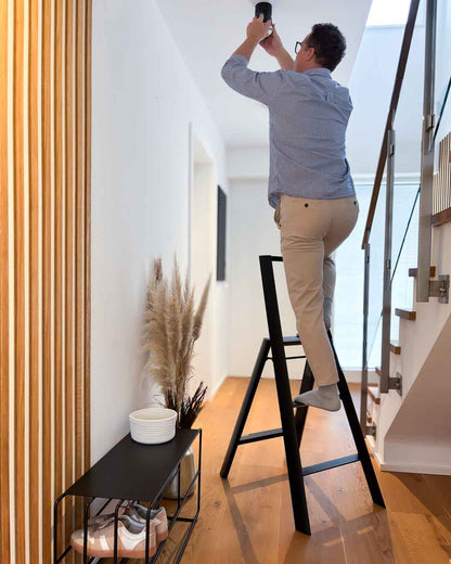 Schwarze Design-Leiter ALVA Trio mit 3 Stufen im Flur mit Person in Anwendung
