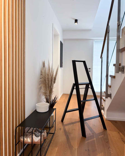 Schwarze Design-Leiter ALVA Trio mit 3 Stufen im Flur neben einer schwarzen Schuhbank