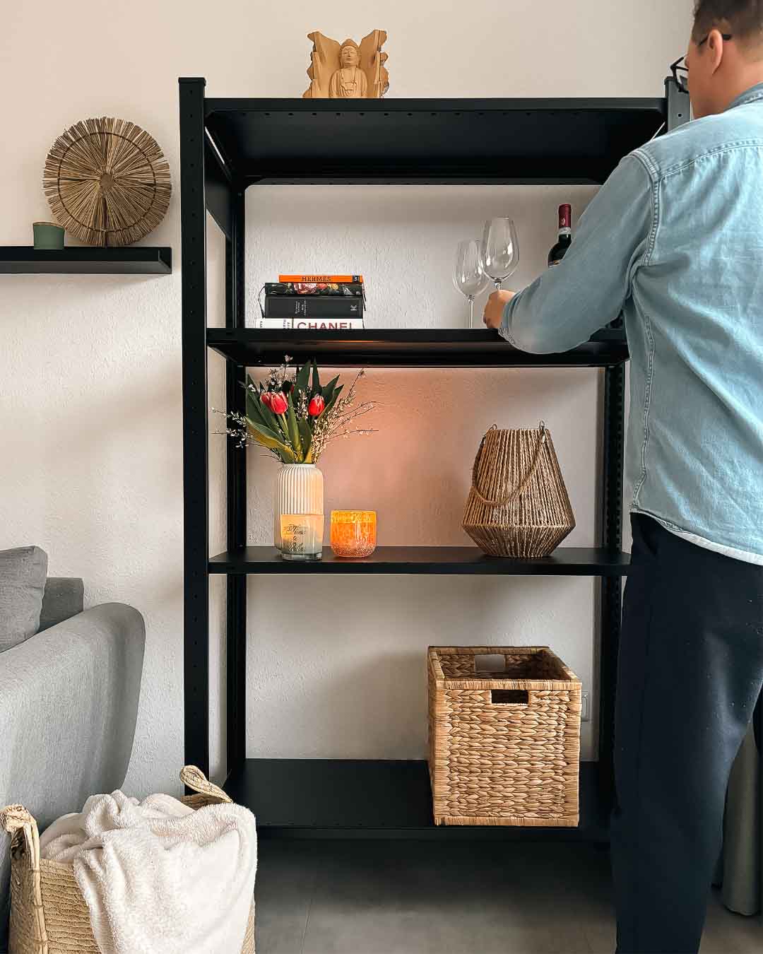 Schwarzes DONIA Design Standregal aus Stahl mit 150 cm Höhe im Wohnraum mit Person in Anwendung