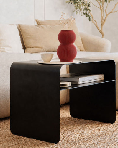 Rote Designvase SHAPE mit Trockenblumen auf dem schwarzen Beistelltisch COSMO in einem modernen Wohnzimmer