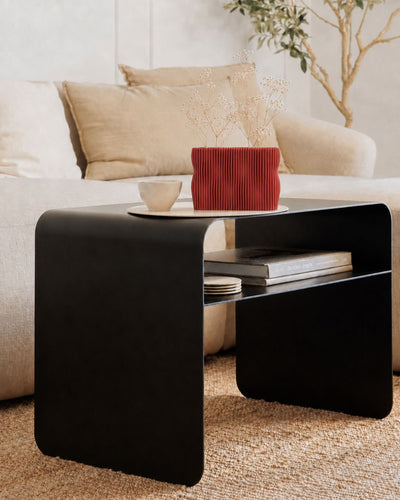 Rote Designvase TWIST mit Trockenblumen auf dem schwarzen Beistelltisch COSMO in einem modernen Wohnzimmer