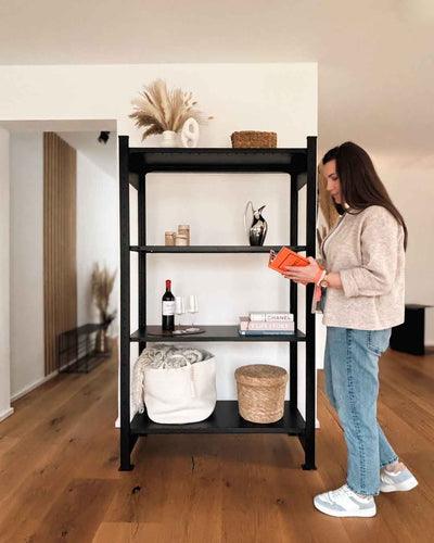 Schwarzes MICA Design Standregal aus Stahl mit 180 cm Höhe im Wohnraum mit Person in Anwendung