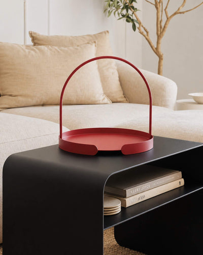 Rotes Serviertablett ARCO auf schwarzem COSMO Beistelltisch in modernem Wohnzimmer mit beigem Sofa.