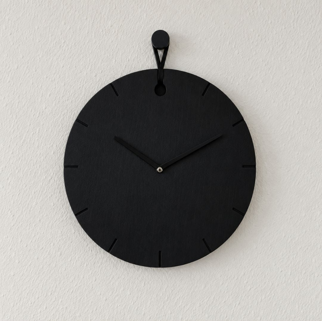 Wanduhr Big Hug in Schwarz an weißer Wand hängend