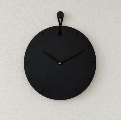 Wanduhr Big Hug in Schwarz an weißer Wand hängend